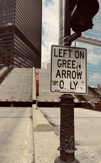 Text on road sign against built structures