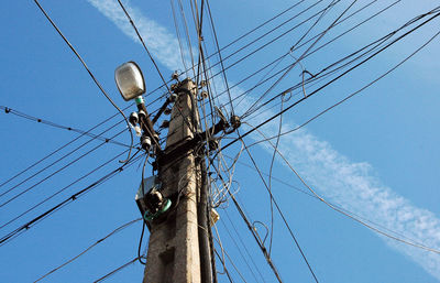 Low angle view of electricity pylon against blue sky