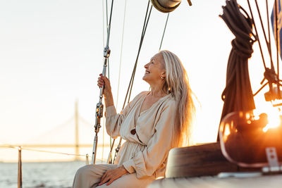 Beautiful senior woman in boat sailing on sea against sky