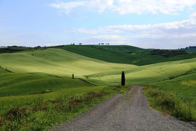 Road amidst green landscape against sky