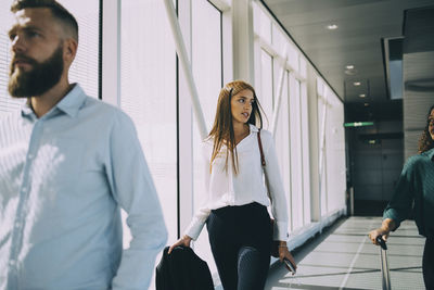 Young businesswoman talking with female colleague while walking in corridor at airport