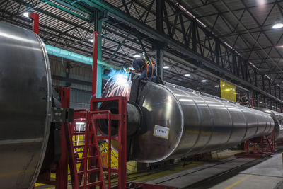 Man welding large steel tank in factory