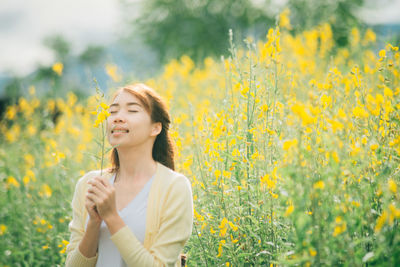 Young woman smelling yellow flower