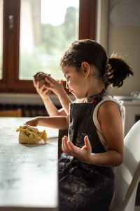 Side view of a sitting girl wearing grey apron