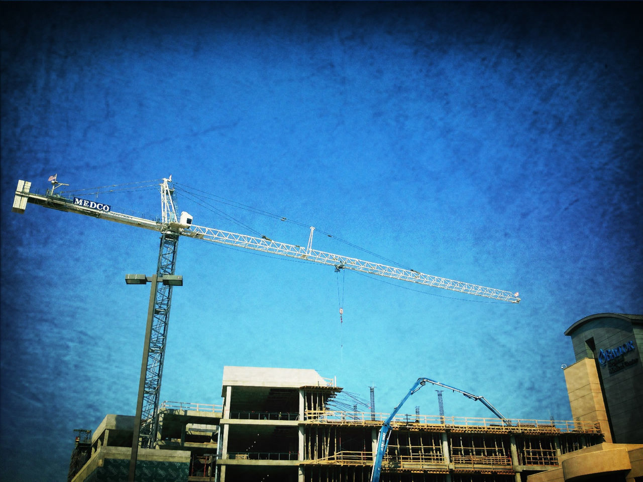 low angle view, built structure, architecture, building exterior, construction site, crane - construction machinery, development, construction, industry, clear sky, crane, blue, communication, sky, incomplete, construction industry, fuel and power generation, copy space, technology, outdoors