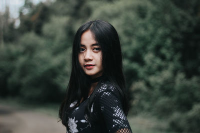 Young woman standing against trees