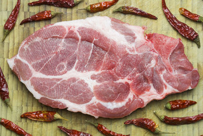 Close-up of pork steak with dried chili pepper on cutting board
