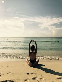 Rear view of young woman in swimwear sitting at beach