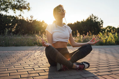 Young woman sitting on footpath