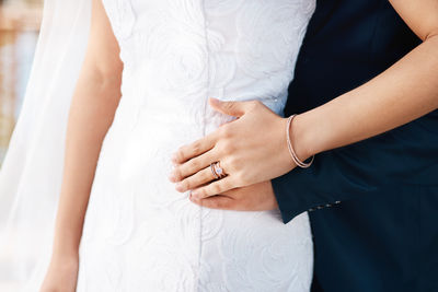 Midsection of bride holding wedding dress