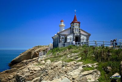 Old church at coastline against sky