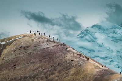 People on mountain against sky during winter