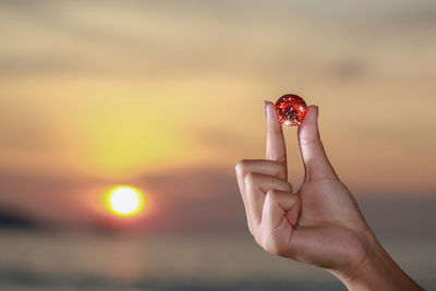 Close-up of person hand holding sun during sunset