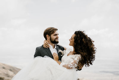 Young couple kissing against sky