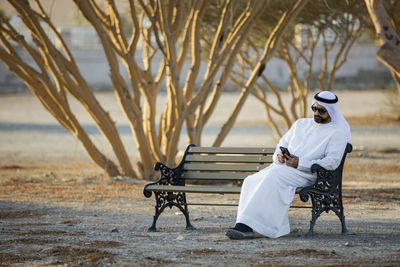 Rear view of man sitting on bench in park