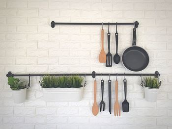 Kitchen utensils and potted plants hanging against wall