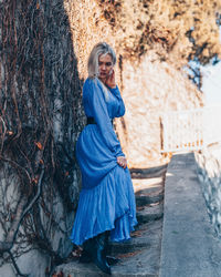 Full length of woman wearing mask against tree trunk