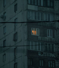 One light, photo of a building exterior with one illuminated window.