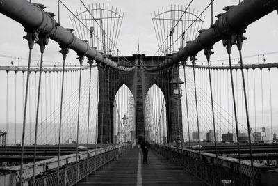 Man walking on brooklyn bridge against sky