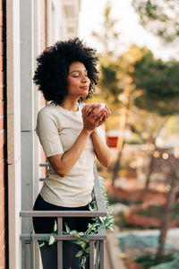 Young woman smiling while standing against wall