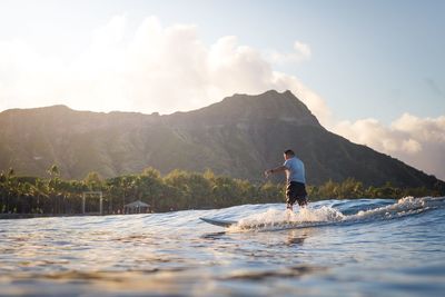 Man in sea by mountains against sky