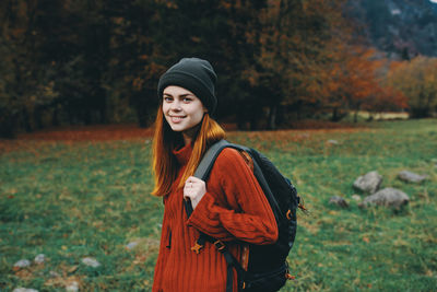 Portrait of smiling young woman standing on field during autumn