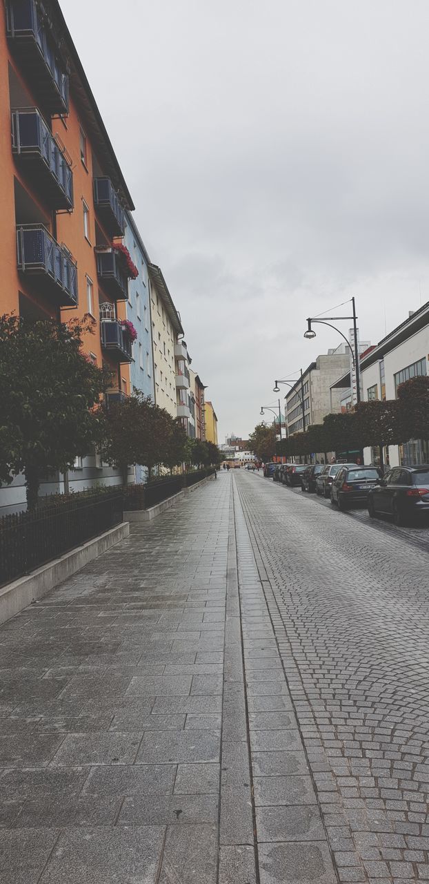 EMPTY ROAD BY BUILDINGS AGAINST SKY