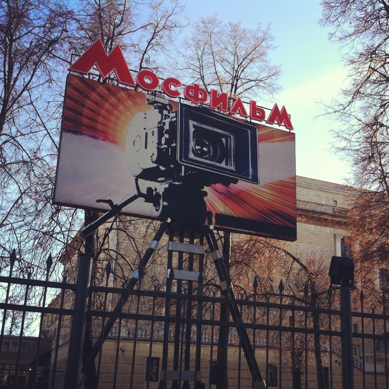 building exterior, architecture, built structure, low angle view, tree, communication, street light, text, bare tree, sky, clear sky, city, guidance, lighting equipment, road sign, outdoors, western script, day, building, no people