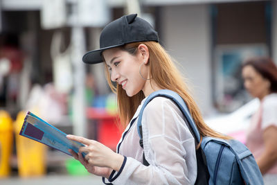 Side view of young woman using mobile phone outdoors