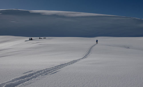 Person skiing on snow covered landscape against sky