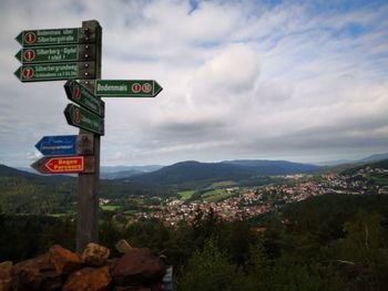 Road sign by mountains against sky