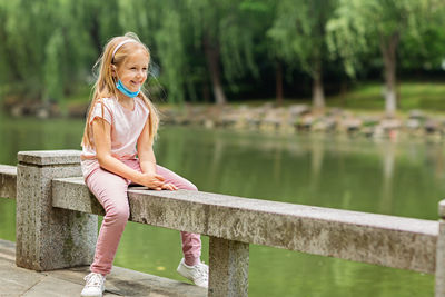 Full length of woman sitting by lake