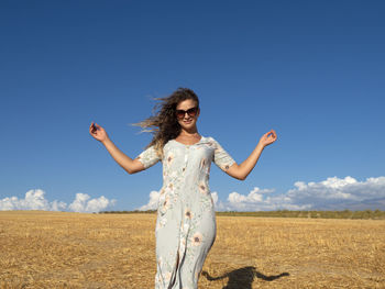 Young woman standing against sky