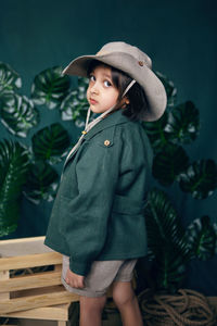 Boy child traveler in a hat stand wooden boxes in a studio on a green background