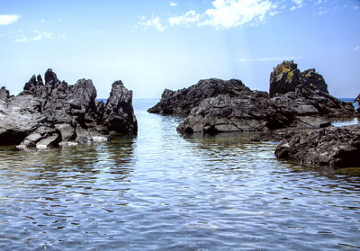 Rocks in sea against sky