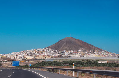 Road by mountain against clear blue sky