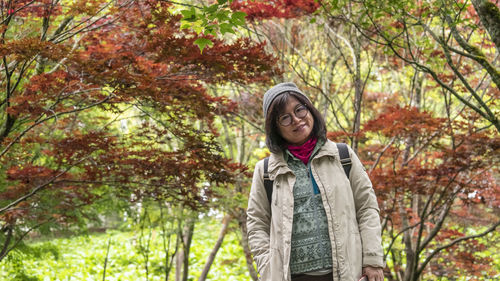 Young woman standing by tree in forest during winter