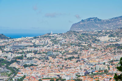 Aerial view of townscape by sea against sky