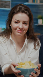 Portrait of smiling woman holding chis in bowl