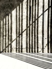 Shadow of metal fence on wall