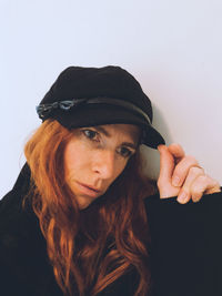 Portrait of young woman wearing hat against white background