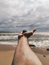 Man relaxing on beach against sky