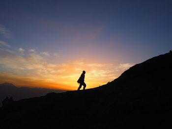 Silhouette man standing on mountain against sky during sunset
