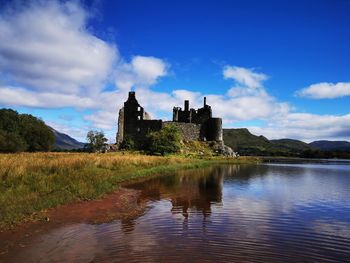 Reflection of building in lake against cloudy sky