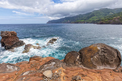 Scenic view of rocks in sea against sky