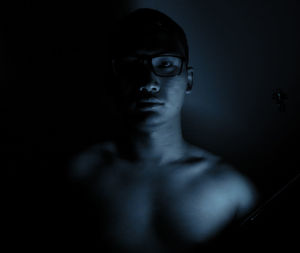 Close-up portrait of serious young man in dark room