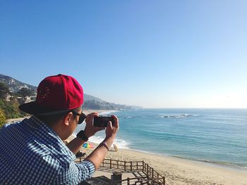 Man photographing sea through mobile phone