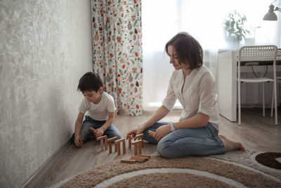 Joint game of mom and son at home, build houses from a wooden constructor. concept childhood 