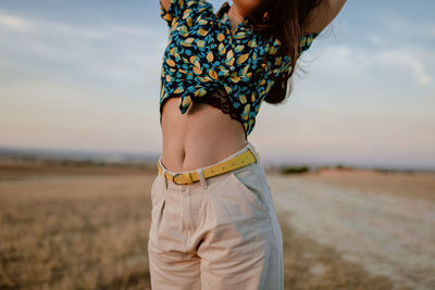 Crop young stylish mindful female under sky at sundown