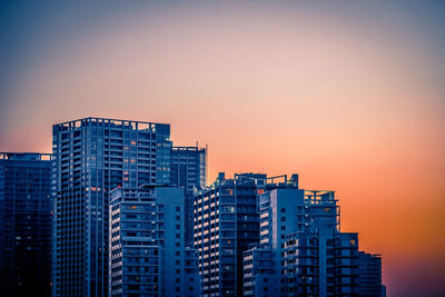 Low angle view of modern buildings against sky during sunset